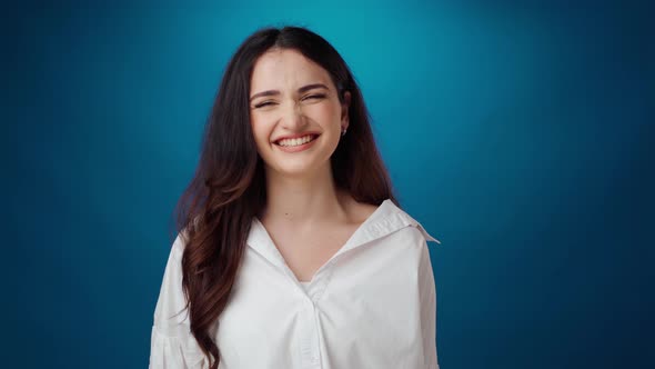Cheerful Young Woman Smiling and Laughing Against Blue Background