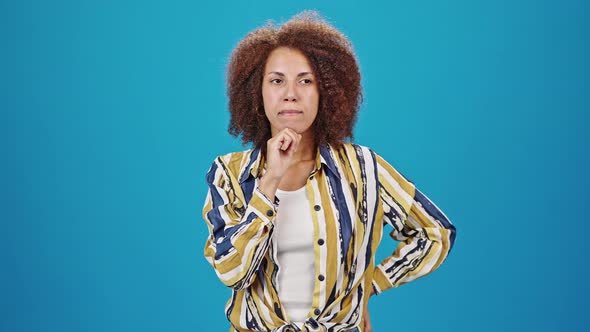 African American Woman Thinks Standing on Blue Background alt
