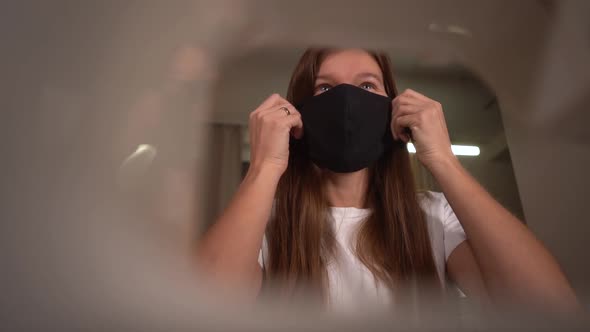 Young Woman Trying a Black Fabric Protective Mask That She Sewed on a Sewing Machine