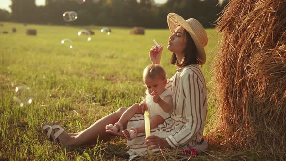 Beautiful mother with her baby blowing soap bubbles
