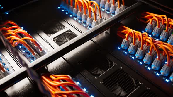Countless orange cables in a  server cabinet lit by a single spotlight. 4KHD alt