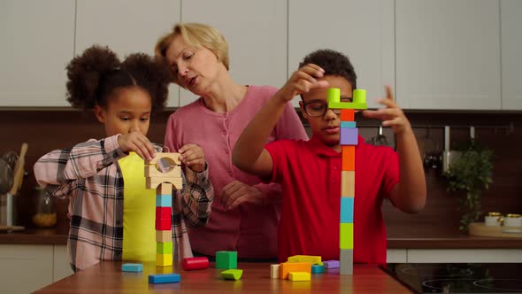 Carefree Multicultural Kids and Grandmother Playing with Toy Building Blocks alt