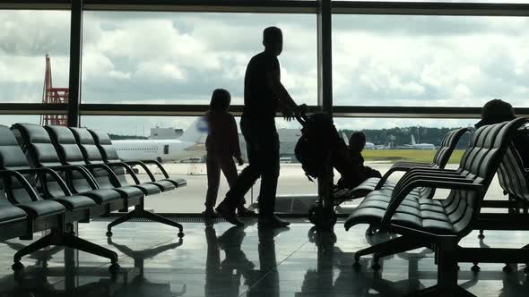 Travelers Walking Along Window in Airport Terminal, People Silhouettes Walking.