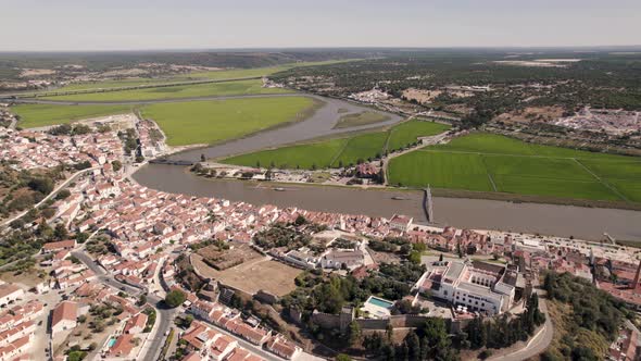 Aerial pan shot of estuary side agriculture rice paddy fields, townscape of Alcacer do Sal alt