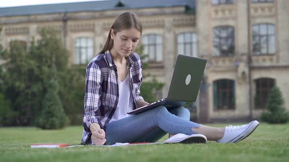 Young Woman Sitting on The Grass with Laptop Computer and Working