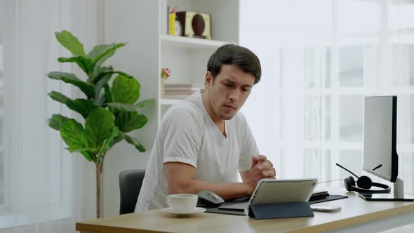 young man in casual clothes is stressed out of working from home on a desk with a computer and table