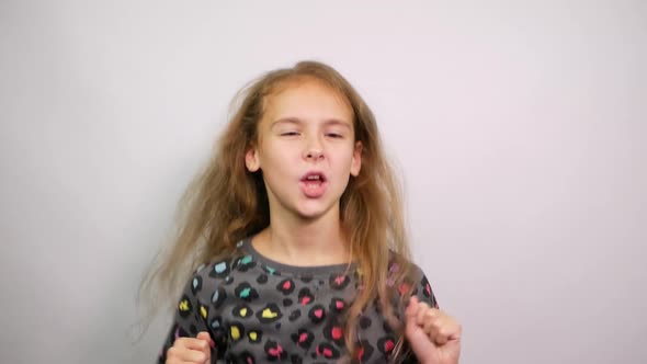 Excited Young Girl Dancing and Raising Hands Up Clenching Fists Doing Winner Gesture alt