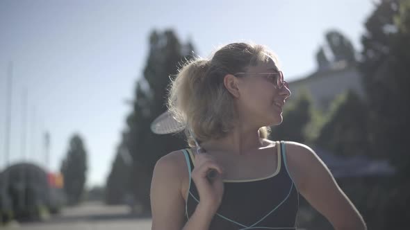 Close-up Portrait of Happy Beautiful Young Woman in Sunglasses Posing with Tennis Racquet in alt