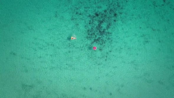 High aerial view of two young girls swimming and playing in sea with inflatables. alt
