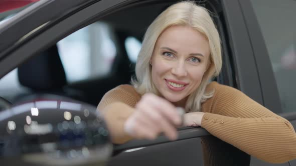 Closeup of Charming Blond Woman with Grey Eyes Looking at Camera Smiling and Opening Car Key alt