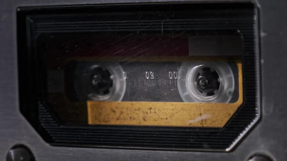 Vintage Yellow Audio Cassette Tape Rotates in Deck of an Old Tape Recorder alt