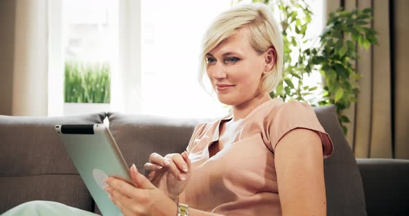 Woman Scrolling Tablet on Sofa