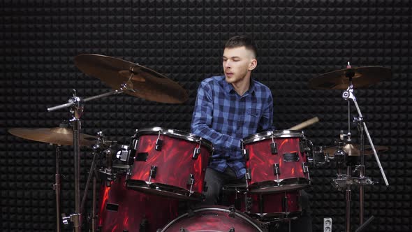 Musician drummer is playing on drum kit on stage at sound recording studio alt