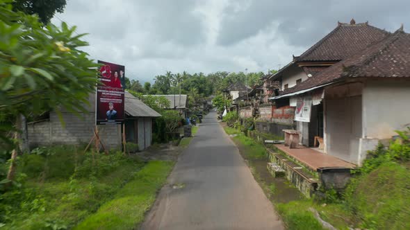 Low Flying Aerial Pov Shot Down the Traditional Street in the Residential Community in Bali alt