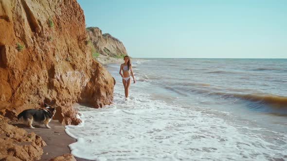Slow Motion Footage of Sexy Fitness Girl in Bikini Walking Along Sand Sea Beach with High Steep Clay alt