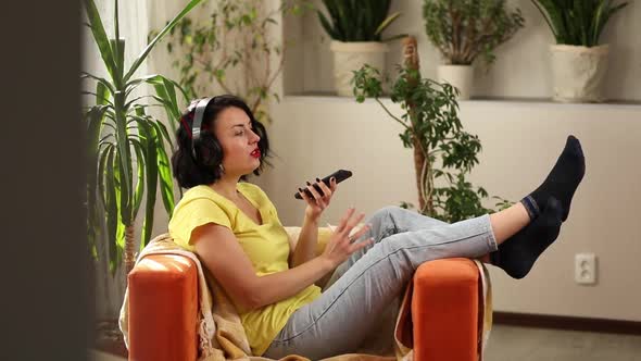 Cheerful woman in casual clothes with headphones and smartphone