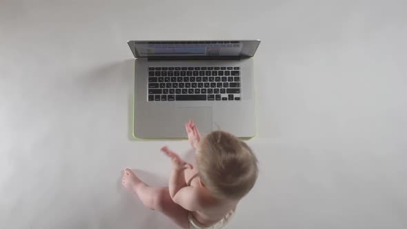 Baby looking at laptop, education concept. Top view