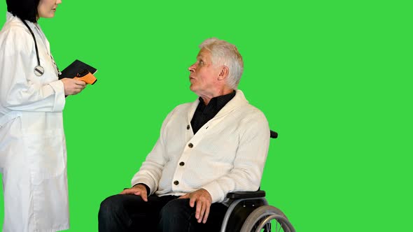 Nurse Measuring Disabled Old Patient's Temperature with Infrared Thermometer in Office on a Green alt