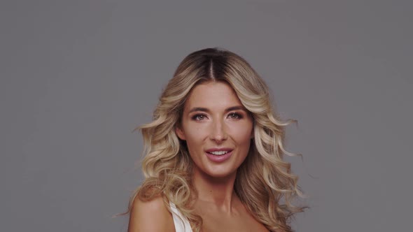 Studio portrait of young and beautiful blond woman over grey background. alt