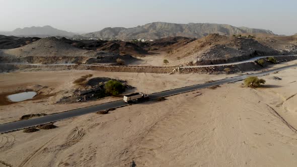 Cargo truck with trailer driving through an empty deserted road highway early morning in Fujairah, U alt