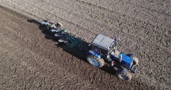 Tractor with a Trailed Plow Cultivating the Soil in Season alt