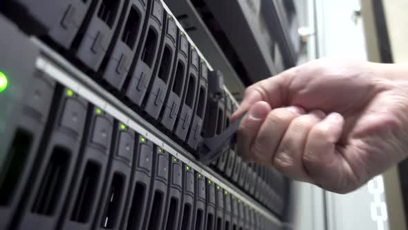 Working Data Center IT Engineer Installs Hard Drive Into Server Rack. .Working Hard Drives. Concept