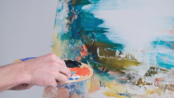 Close Up Shot of the Hand of a Male Artist Holding a Brush and Painting an Oil Painting alt
