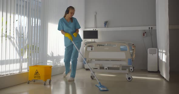 Young Nurse in Headphones Dancing While Washing Floor in Hospital Ward alt