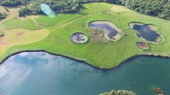 Aerial view of peaceful ponds on a green meadow alt