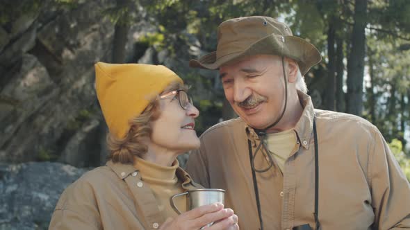 Elderly Couple Drinking Tea and Chatting during Hike alt