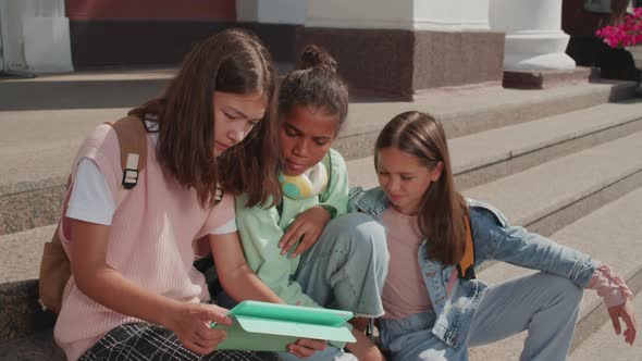 Girls Using Tablet on Steps of School Building alt