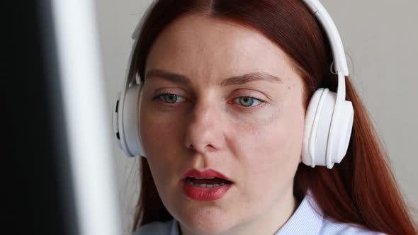 Beautiful Woman in Headphones Having Conversation on Video Chat While Using Computer at Home