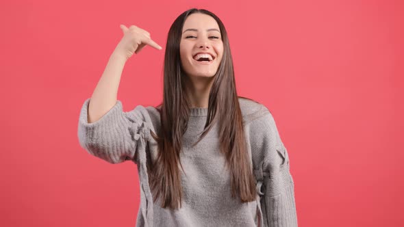 Cute Girl Pointing To You and Doing Talking on the Telephone Gesture alt