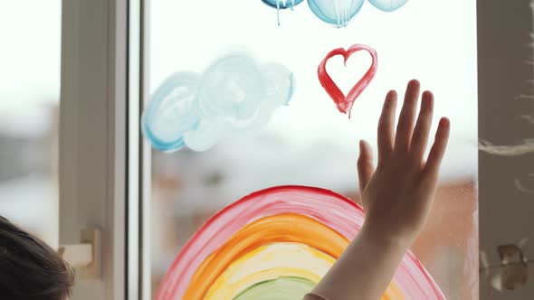 Close Up of Hand of Woman Touching Glass Window with Colorful Painting on It alt