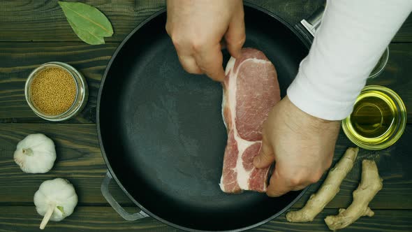 The cook puts the meat on the pan. Sliced pork steaks in a cast iron skillet. A metal frying pan