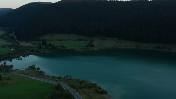 Drone Flying Towards Calm Blue Water In Frumoasa Dam In Romania, aerial tilt down alt