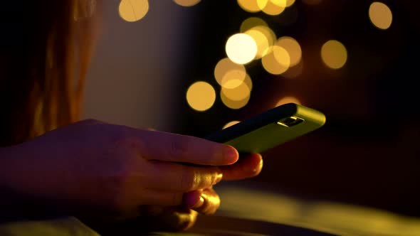 Asian woman using smart phone on the bed at night.