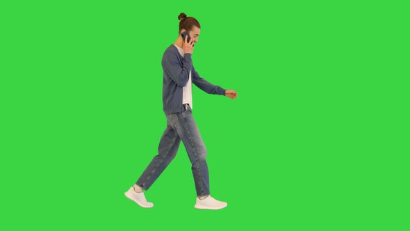 Young White Man Walks Talking on His Smartphone and Smiling on a Green Screen Chroma Key alt