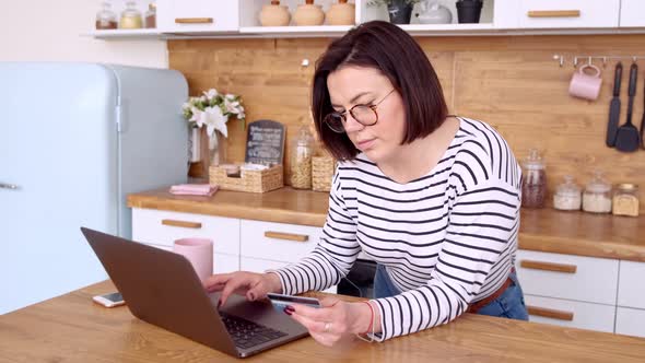 Online banking with laptop. Woman doing online shopping with credit card while at home alt