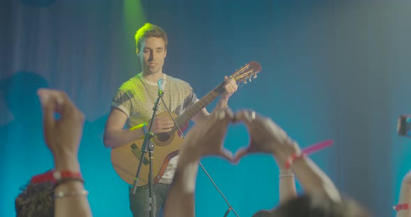 Man playing guitar in front of audience at nightclub