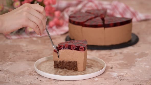 Piece of delicious chocolate mousse cake with cherry jelly on top.