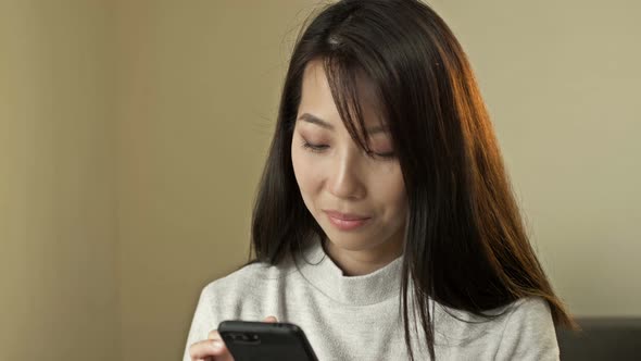 Portrait of a Young Asian Woman with a Mobile Phone in Her Hands alt