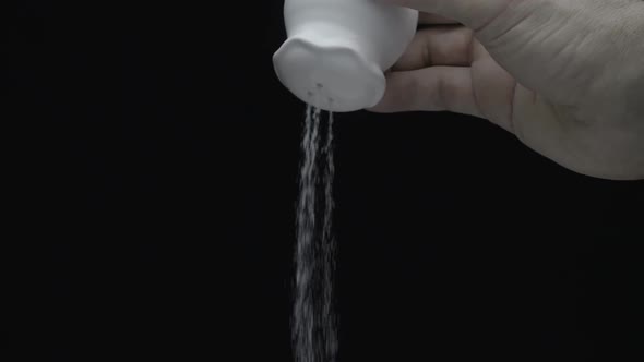 Hand Shakes The Salt Cellar And Salted Food On A Black Background. Slow Mo 2