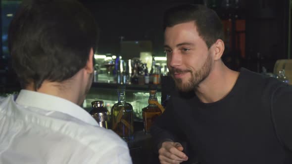 Young Male Friends Talking While Having Drinks Together at the Bar