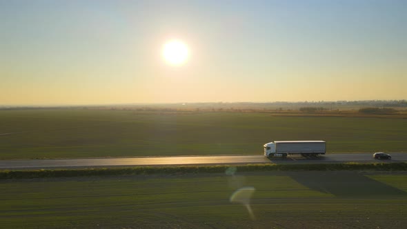 Aerial View of Semitruck with Cargo Trailer Driving on Highway Hauling Goods in Evening alt