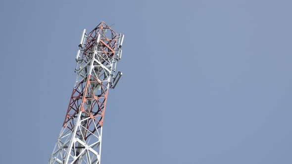 Wireless repeater tower against blue sky slow tilt 4K 2160p 30fps UHD footage - Celluar base station