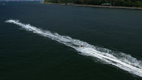 Chasing jet skis under the Verrazano Bridge from a left profile to center  as they enjoy the waves o alt