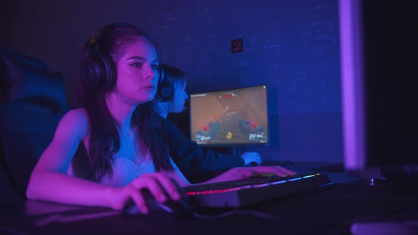 Two Pretty Gamer Girls Playing an Online Shooter Game in the Dark Neon Gaming Club alt
