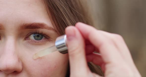 close-up of the girl's face, half of the face in the frame, skin care, applying serum with a glass p alt