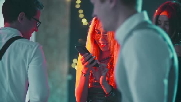 Portrait of Caucasian Blonde Girl Addicted to Phone While Dancing at Party alt